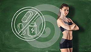 Fitness girl on background of blackboard with sign that prohibit dry protein and pills photo