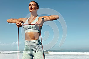 Fitness Girl On Beach Portrait. Stretching Workout With Resistance Loop On Tropical Ocean Background.