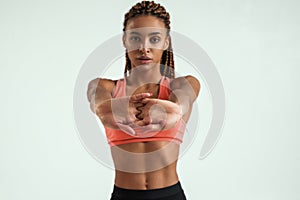 Fitness girl. Beautiful young african woman in sportswear stretching her arms and looking at camera while standing