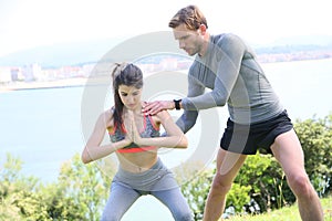 Fitness girl with coach doing excercises outdoors