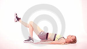 Fitness girl doing glut bridge with leg rise side view. Sports video tutorials isolated on white. Health care concept