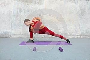 Fitness Girl Doing Twisting Exercise On Yoga Mat At Outdoor Stadium. Fit Woman With Strong Muscular Body.