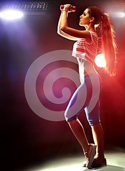 Fitness girl exercising in gym with dumbbells.