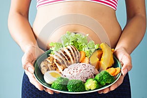 Fitness girl holding healthy food on dish. Selective focus