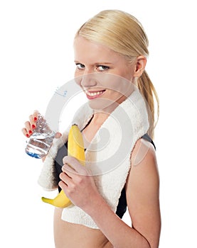 Fitness girl holding water bottle and banana