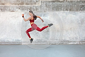 Fitness Girl Jumping. Outdoor Workout Against Concrete Wall At Stadium. Fashion Sporty Female With Strong Sexy Body.