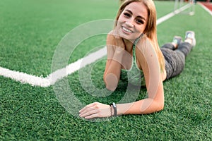 Fitness girl lying on the grass of a soccer field.