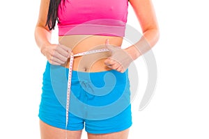 Fitness girl measuring her waist. Close-up.