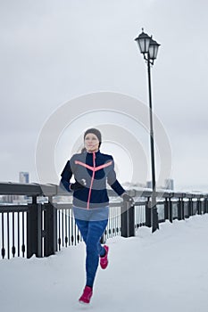 Fitness girl model running at snow outdoor, jogging