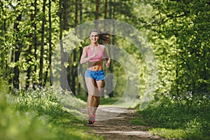 Fitness girl running on forest trail and smiling