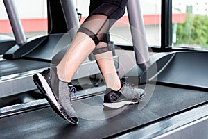 Fitness girl running on treadmill, Woman with muscular legs in g