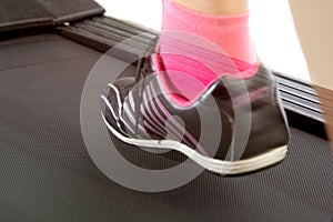 Fitness girl running on treadmill. Woman with muscular legs on w