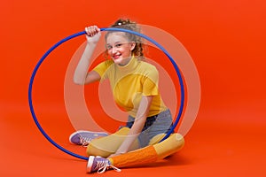 Fitness girl sitting on floor with hula hoop