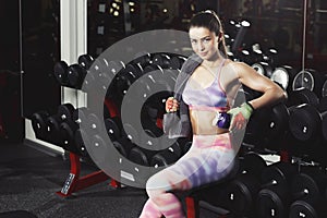 Fitness girl with towel and shaker relaxing in the gym