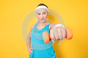 Fitness girl training gym with dumbbell, isolated on yellow background. Half length of fit sportswoman lifting weights. Fitness