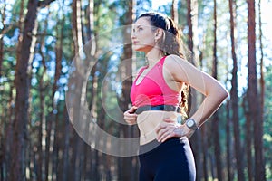 Fitness girl using heart rate monitor for workout in the forest or tracking her weight loss improvement