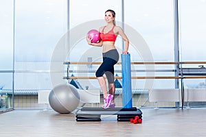 Fitness girl, wearing in sneakers, red top and black breeches, posing on step board with ball, the sport equipment