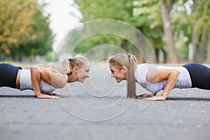 Fitness girls doing push-ups outdoors on a park background. Sporty girls. Workout concept. Copy space.