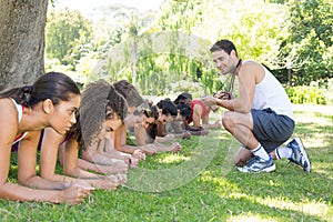 Fitness group planking in park with coach photo