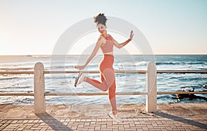 Fitness, happy running and woman jumping on beach path on fun morning exercise with freedom and happiness. Run, jump and