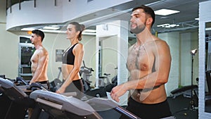 Fitness happy woman and man on stationary bicycle doing spinning at gym. Fit young woman working out on bike with man