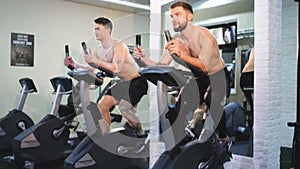 Fitness happy woman and man on stationary bicycle doing spinning at gym. Fit young woman working out on bike with man