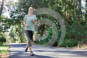 Fitness, health and a running senior woman on a road through a forest or park for cardio and endurance. Exercise, mockup