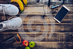 Fitness and healthy active lifestyle background concept.  Training sneakers,  water bottle, apples, bananas, smartphone and