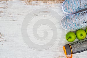Fitness and healthy active lifestyle background concept.  Training sneakers,  water bottle and green apples on grunge white wooden