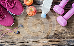 Fitness, healthy and active lifestyles Concept, dumbbells, earphones, sport shoes, bottle of milk, apples on wood background. top