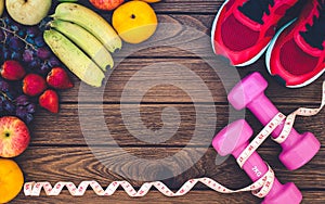 Fitness, healthy fruits, diet and active lifestyles Concept, dumbbells, tape measure, sport shoes, fresh fruits on wood
