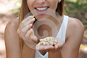 Fitness healthy girl outdoors. Close up of young woman eating pistachios in the park. Selective focus on her mouth