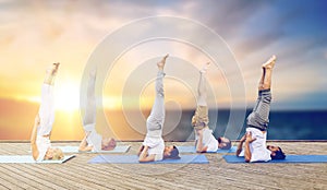 People doing yoga shoulderstand on mat outdoors