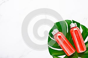 Fitness, healthy nutrition diet concept. Fresh cool watermelon juice in a glass jar and tropical monstera leaf on a light