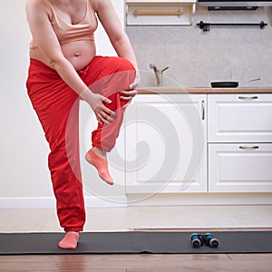 Fitness at home during pregnancy and problems with getting a leg injury. Pregnant woman at sports training holds on to a bruised