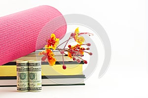 Fitness industry success symbolized in yoga mat, books, flowers, and currency