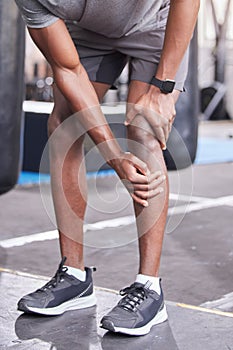 Fitness, injury and knee pain of black man at gym with inflammation problem resting legs. Joint pain, accident and