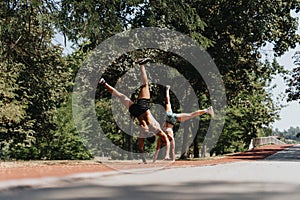 Fitness Inspiration in Natural Environment: Sports Duo Exercising Muscles and Doing Cartwheel Together in Park