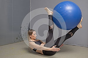 Fitness instructor demonstrates how to do the exercises in a gym with fitness ball