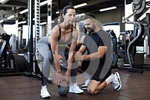 Fitness instructor exercising with his client at the gym