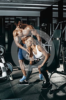 Fitness instructor exercising with his client at the gym.