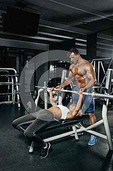 Fitness instructor exercising with his client at the gym.