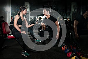 Fitness instructor exercising with his client at the gym, Personal trainer helping woman working with heavy dumbbells