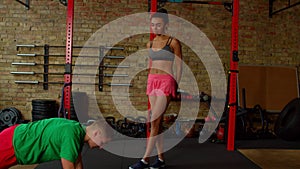 Fitness instructor explaining and showing exercise to fit woman in health club