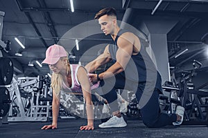 Fitness instructor help girl to do push ups on training in fitness center