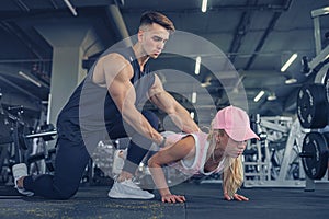 Fitness instructor help girl to do push ups on training in fitne