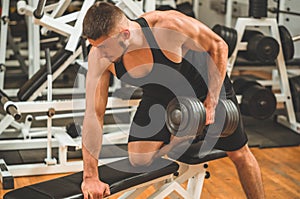 Fitness instructor in the sport room background. Male model with muscular fit and slim body