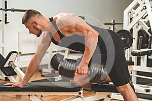 Fitness instructor in the sport room background. Male model with muscular fit and slim body