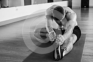 Fitness instructor in the sport room background. Male model with muscular fit and slim body