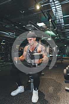 Fitness instructor in the sport room background. Male model with muscular fit and slim body. Sport concept